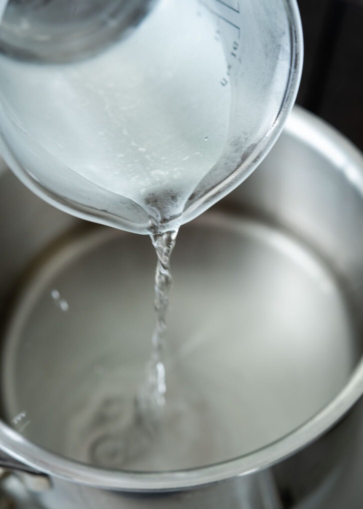 Vinegar added to sugar water mixture in a pot.